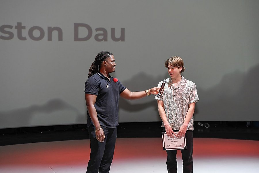 a person holding a microphone for a person wearing a patterned collared shirt