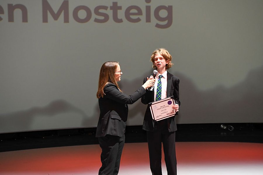 one person holding a microphone for person wearing a suit and tie