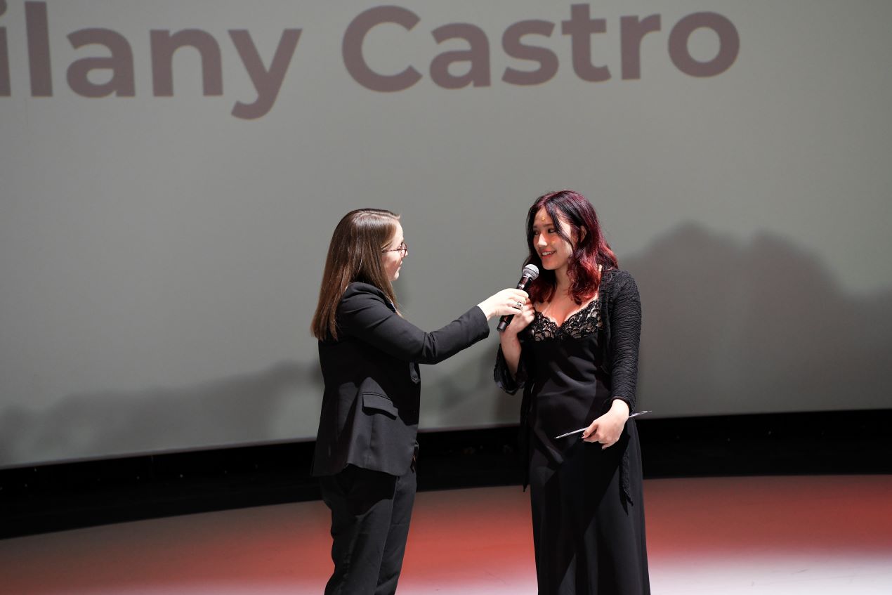 one person holding a microphone for a person wearing a dress